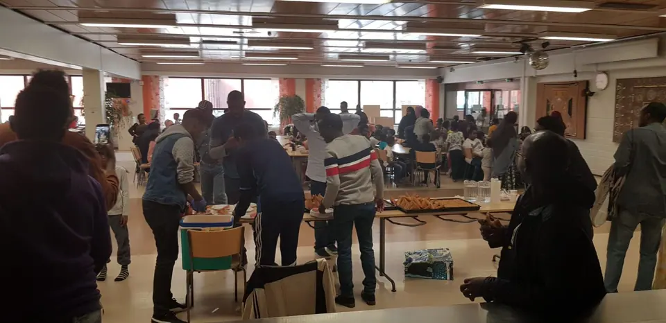 Osallistujat kokoontuvat yhteiseen tilaan pöytien ympärille.